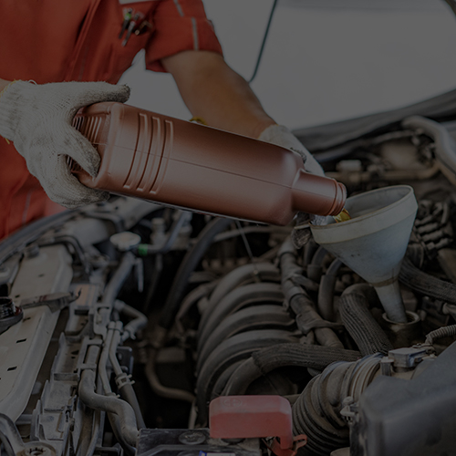 Car mechanic pouring fresh oil into engine